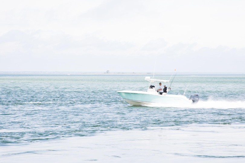 Middle-aged man driving a boat in the ocean with his son.